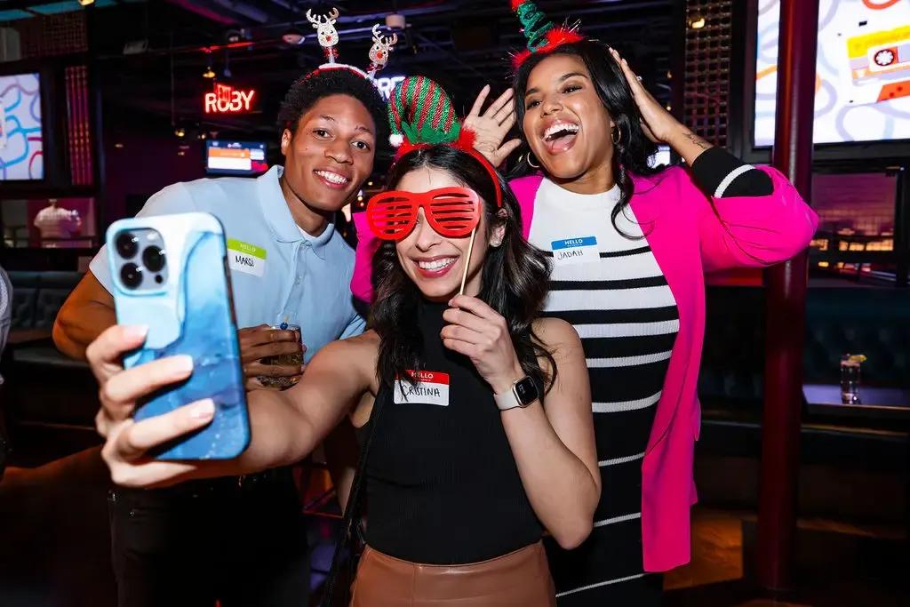 3 guests at puttshack taking a selfie with holiday props