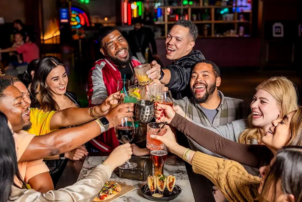 A group of friends doing a drink cheers at Puttshack 